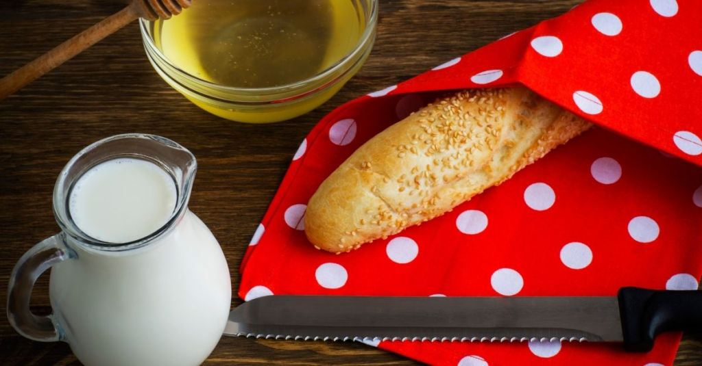 Serrated bread knife next to a baguette, used for clean slices through bread and pastries.