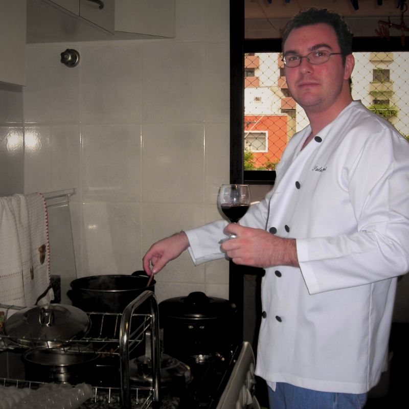 Tom, cooking at home 17 years ago, enjoying a glass of wine while preparing a meal, symbolizing his early passion for cooking.