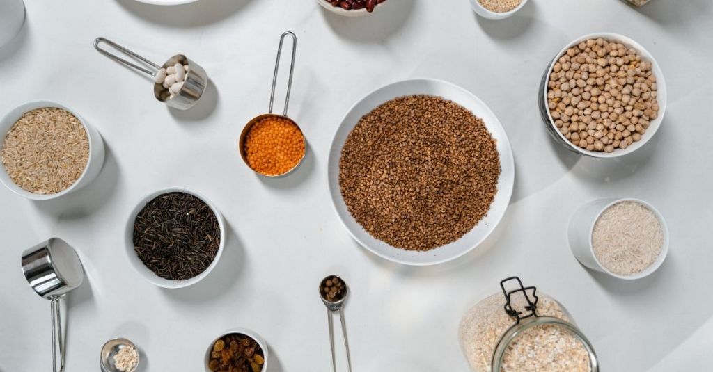 Assorted measuring tools with grains, spices, and legumes for diverse recipe preparations.