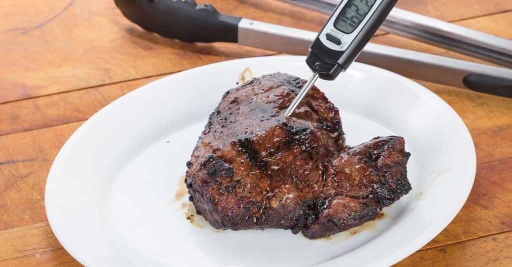 Meat thermometer checking steak temperature, ideal for achieving precise doneness levels.