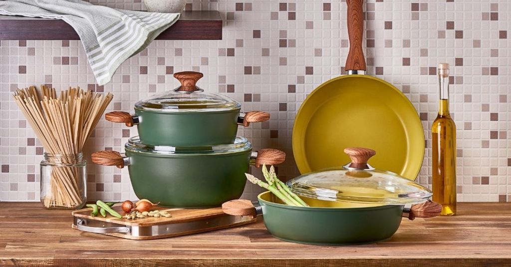 Green pots and pans set with wooden handles displayed on a kitchen counter