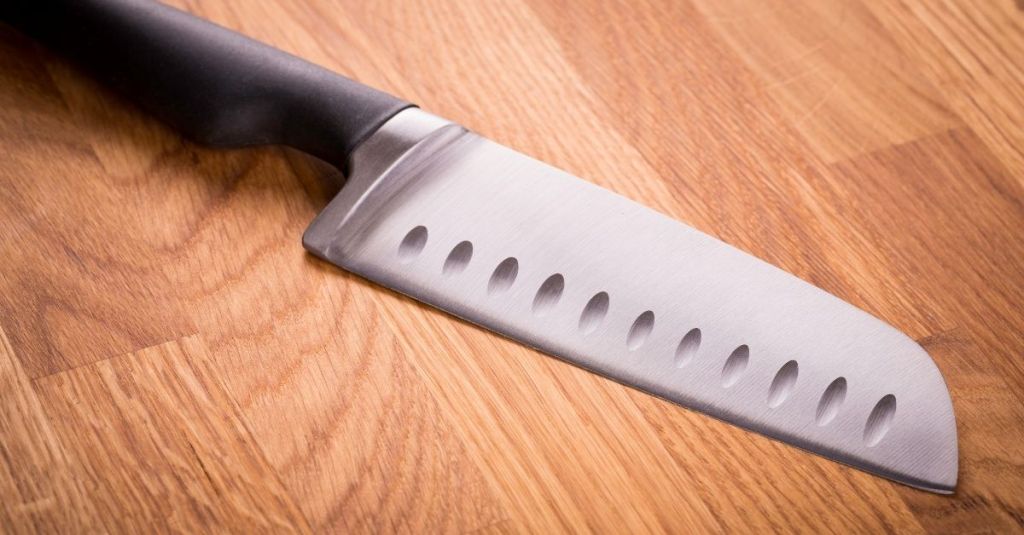 Santoku knife with a sharp blade and hollow edge design on wooden surface