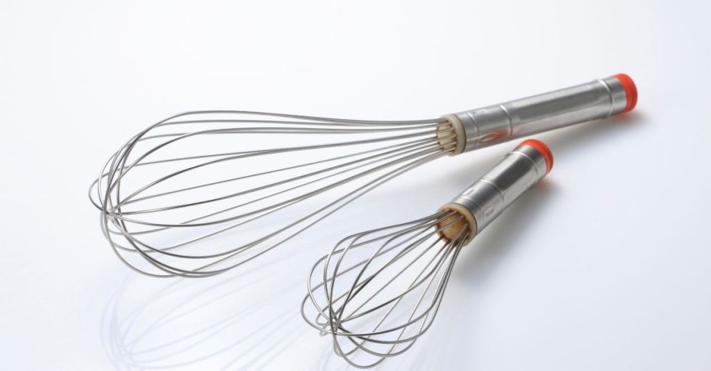 Two stainless steel whisks of different sizes, used for mixing ingredients in the kitchen.
