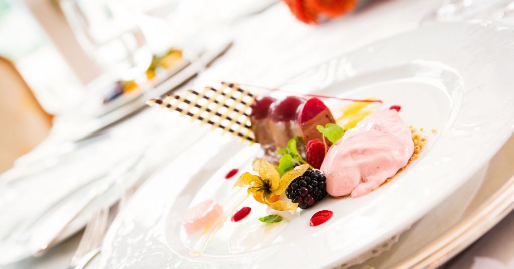A gourmet dessert plate with chocolate mousse, pink ice cream, and fruit gels, showcasing an elegant presentation.