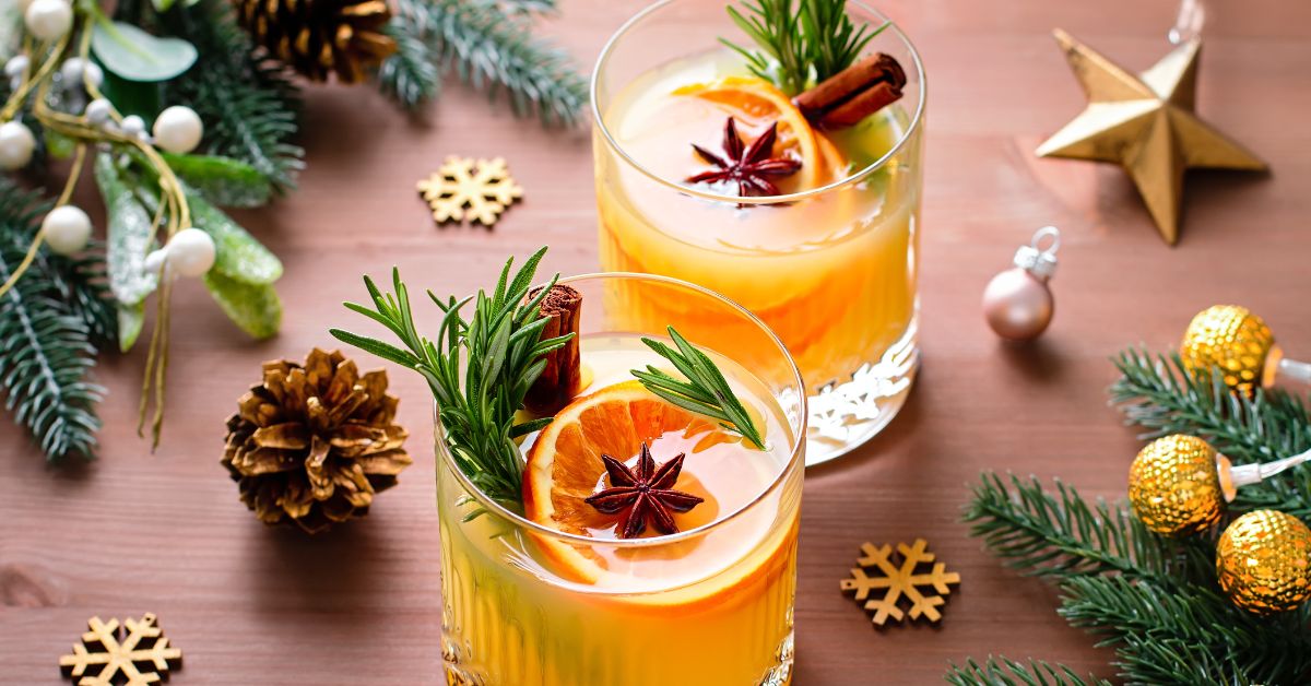 Non-alcoholic holiday mocktail garnished with cinnamon sticks, star anise, and rosemary sprigs.