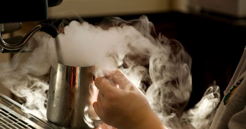 Steaming milk with foam rising, essential for cappuccino.
