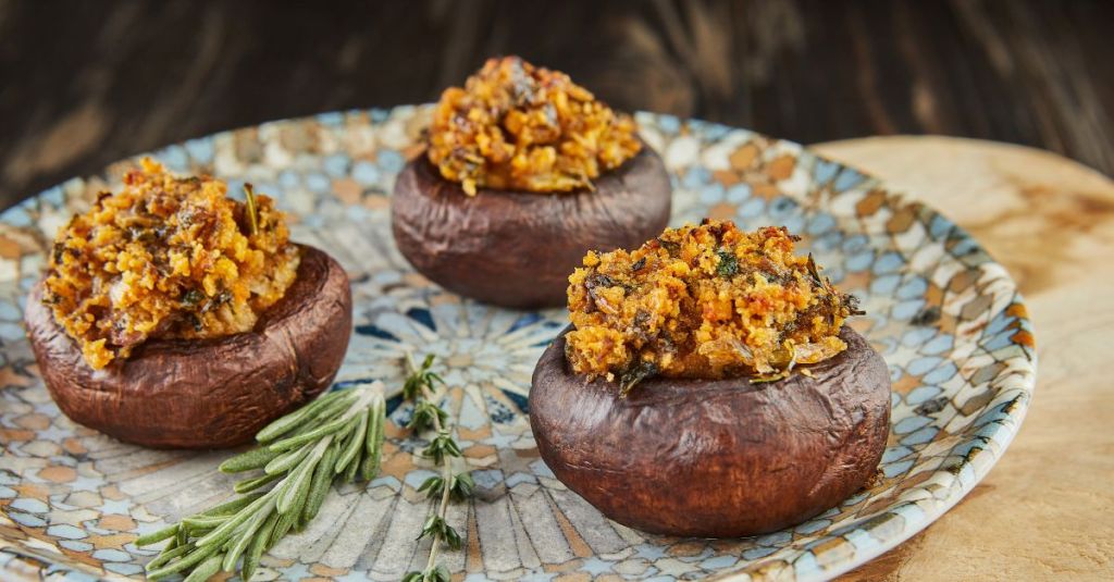 Savory stuffed mushrooms topped with an herb mixture, ready to serve as an enticing appetizer for a plant-based holiday dinner.