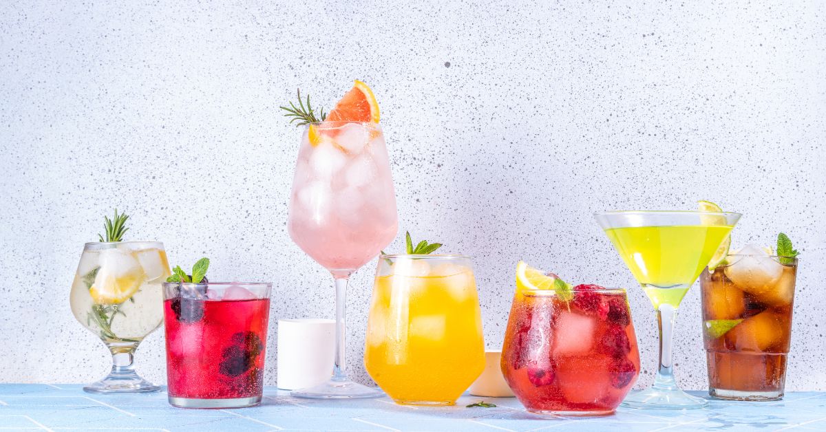 Non-alcoholic mocktails in different colors with citrus, herbs, and ice in assorted glassware.