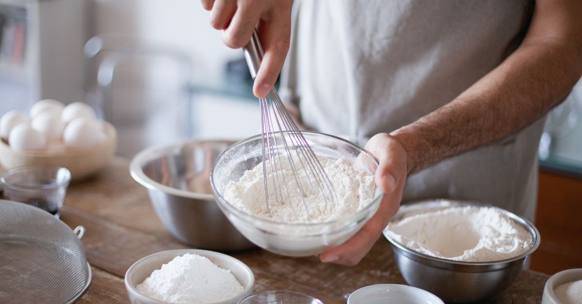 Whisking flour for quick and healthy breakfast preparation. Preparing batter with flour and utensils, perfect for quick and energy-boosting breakfast recipes.