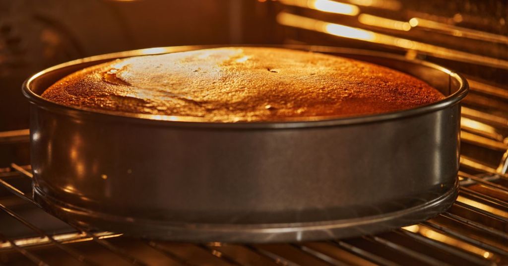 cheesecake baking in springform pan Cheesecake in a springform pan baking in the oven, its surface turning golden brown under the warm light.