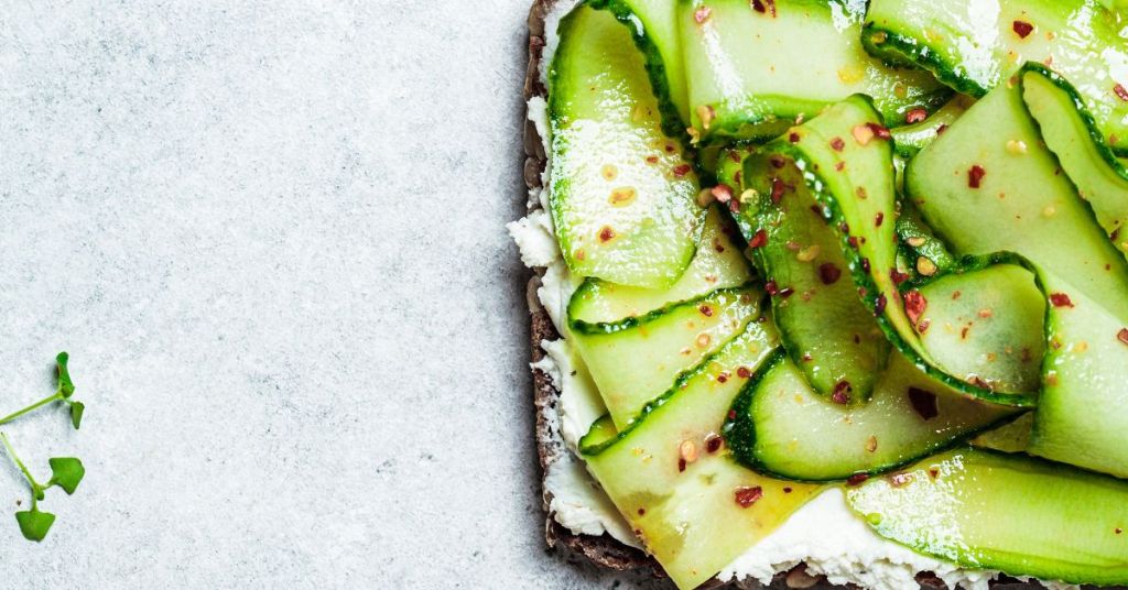 Healthy cucumber toast with cheese and chili flakes, a savory energy boosting breakfast idea. A close-up of a whole-grain toast layered with creamy cheese, fresh cucumber slices, and chili flakes, ideal for a quick and healthy breakfast idea.