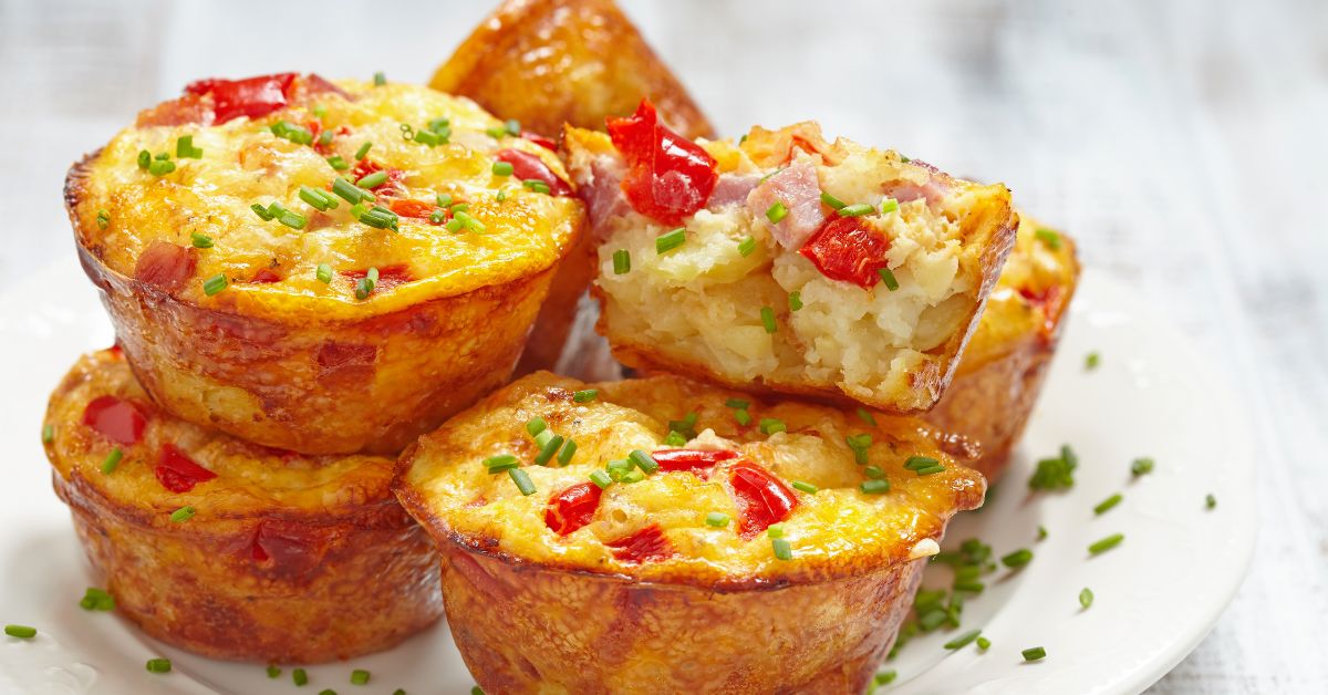 Savory egg muffins with colorful vegetables and diced ham, topped with fresh chives – a convenient and energy-boosting breakfast option. Savory egg muffins packed with vegetables and ham, a quick breakfast for sustained energy.