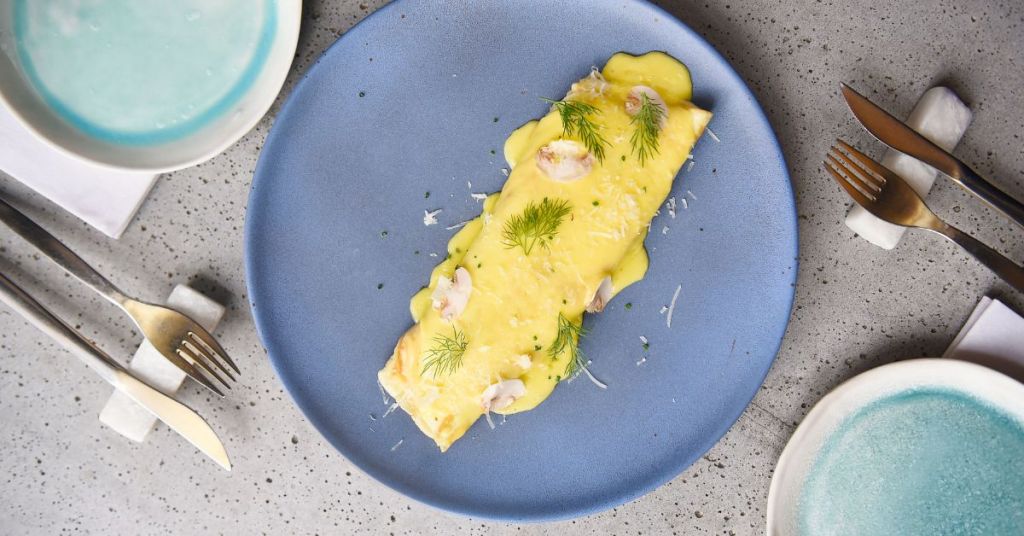 A delicate French egg creation covered in a rich cream sauce and garnished with fresh dill for a refined finish.