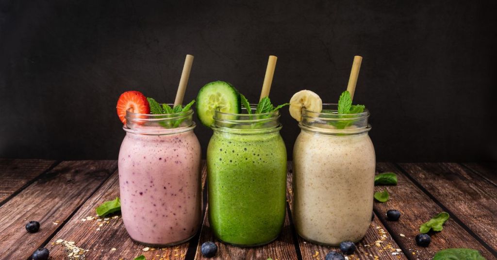 Three smoothies made with fresh fruits, spinach, and protein powder for an energizing morning meal. Three jars of smoothies in vibrant flavors—strawberry, banana, and spinach—perfect for a healthy and quick breakfast.