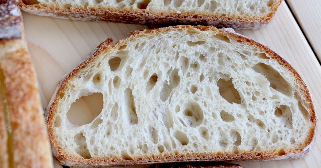 A close-up of a sourdough bread slice with a light, open crumb and golden crust, highlighting the results of proper fermentation.