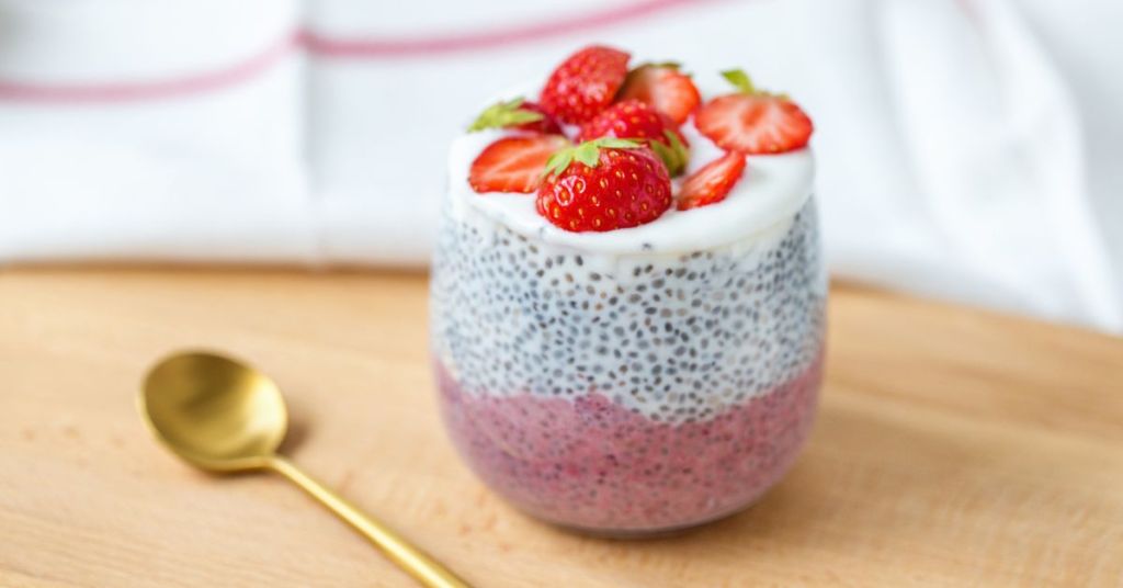 Chia pudding layered with yogurt and strawberries, a refreshing energizing morning meal. A glass of chia pudding topped with fresh strawberries and yogurt, a delicious and energizing morning meal.