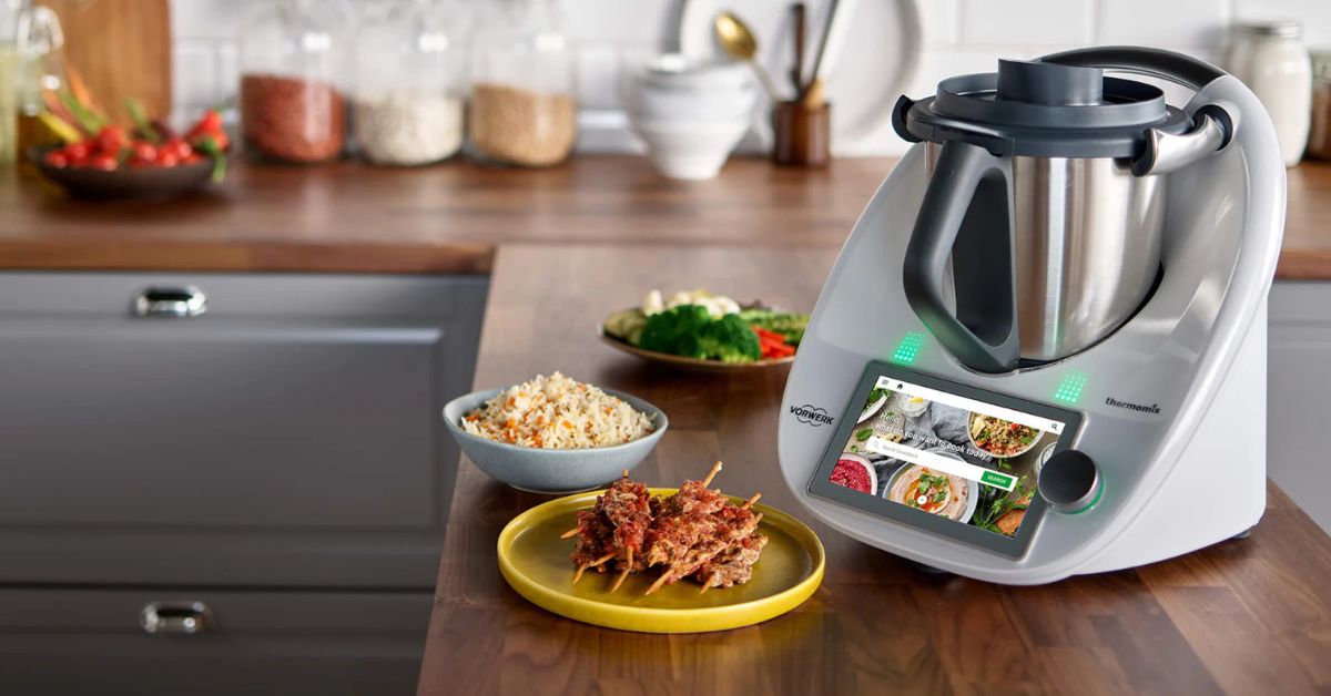 Thermomix multifunctional kitchen appliance on a countertop with prepared dishes, ideal for modern cooking.
