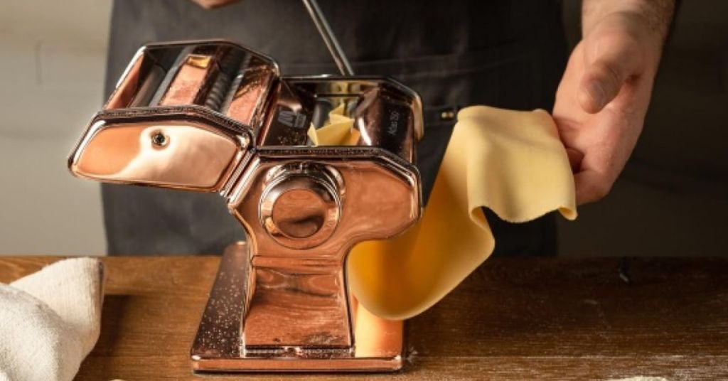 Marcato Atlas pasta machine rolling fresh dough into sheets, perfect for various pasta shapes.